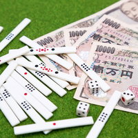 萬札と散らばる麻雀牌とサイコロの写真