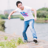 河川敷を走るように動く白Tシャツの男性の写真