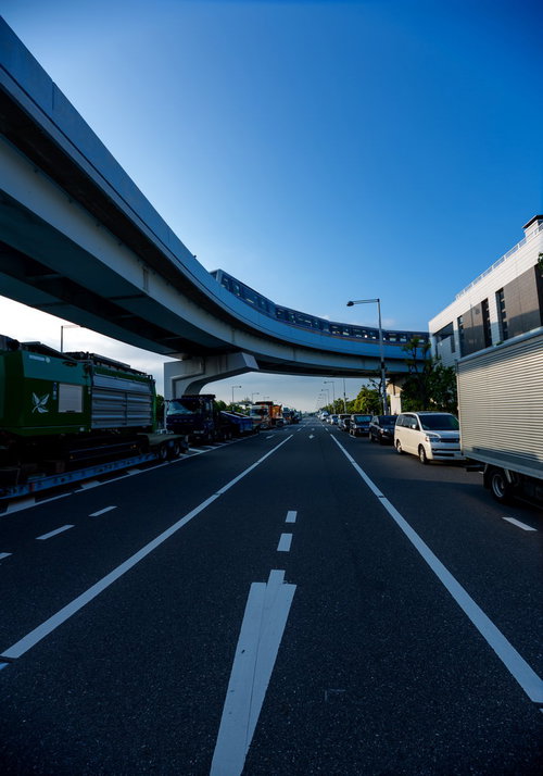 高架のモノレールと地上で渋滞する車の列が並ぶ都市風景