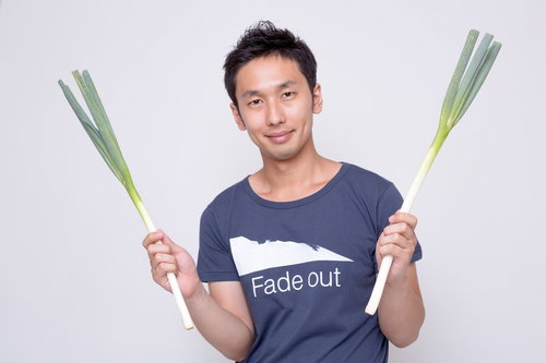 両手にネギを持つ紺Tシャツの男性