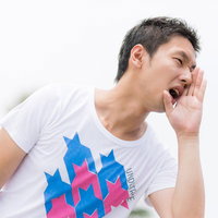 口元に手を当てて大声で叫ぶ男性の写真