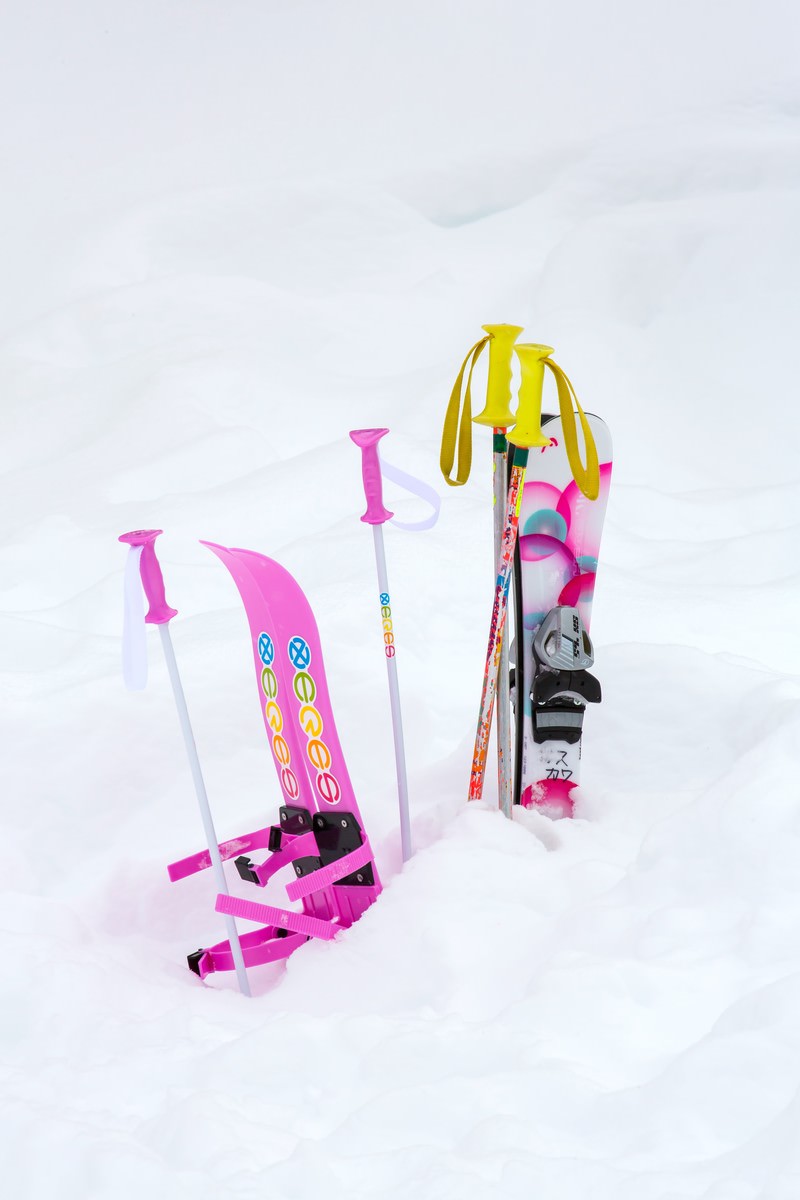 雪の上に立つピンクのキッズ用スキー板とカラフルなストック