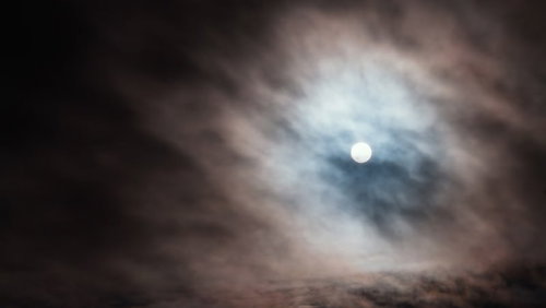 厚い雲の中から覗く満月