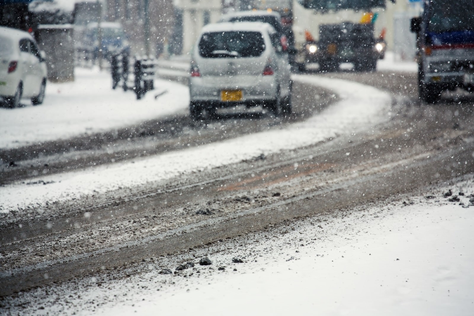 降雪時に積雪した道路を走行する自動車群