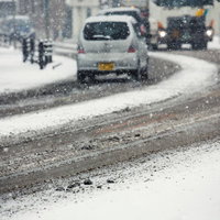 雪が降る道路を走る車列の写真