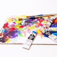 パレットに並ぶ絵具チューブと筆の写真