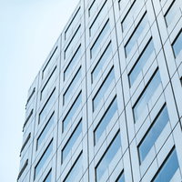 青空を背景にした高層オフィスビル、規則正しい窓配置の写真