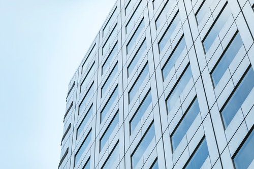 青空を背景にした高層オフィスビル、規則正しい窓配置