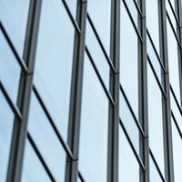 オフィスビルの格子状に並ぶガラス窓と青空の反射の写真