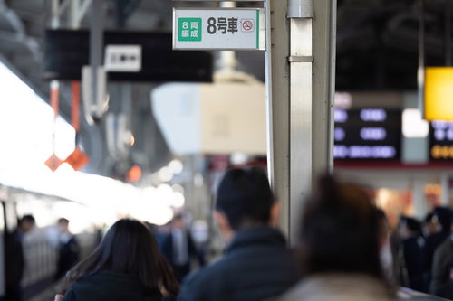 駅ホームの緑色乗車位置案内板と通勤ラッシュの人混み