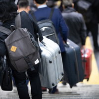 重たいスーツケースを持って階段を下りるトラベラーの移動シーンの写真