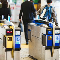駅構内の青と黄色の自動改札機でICカード利用する乗客の写真