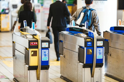 駅構内の青と黄色の自動改札機でICカード利用する乗客