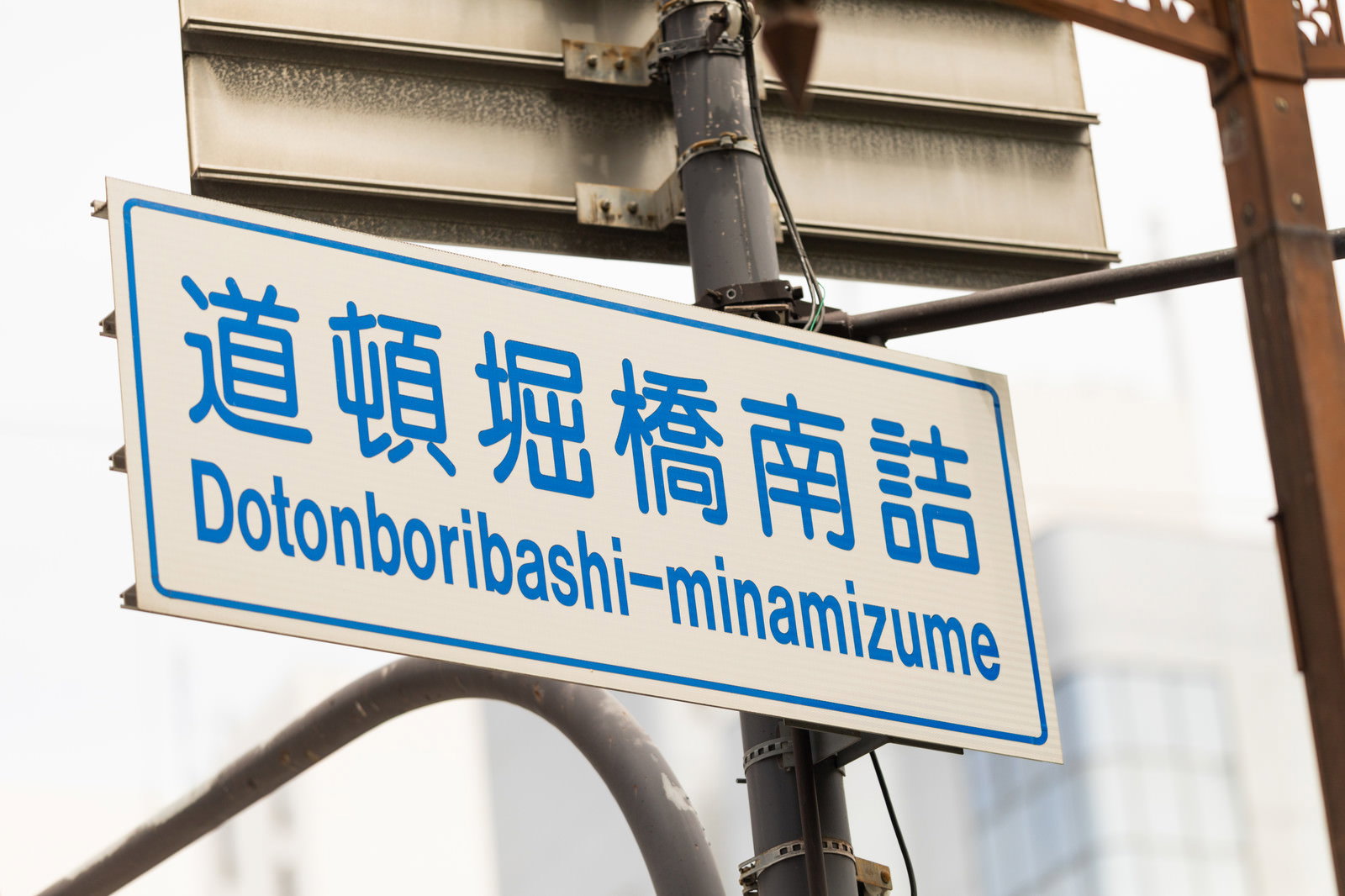 青い背景に白文字で道頓堀橋南詰と書かれた街角の案内看板