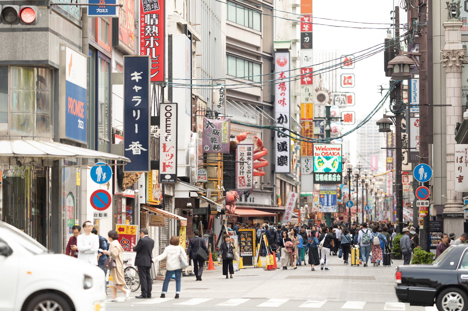 道頓堀の繁華街を歩く多くの人々と色とりどりの看板が並ぶ賑やかな街並み