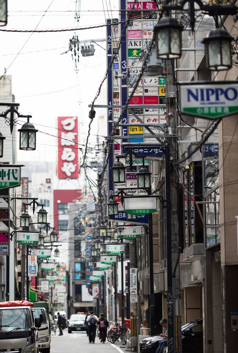 心斎橋東通りの昼間の街並み。狭い通りに店舗看板が密集し、頭上に電線と街灯が張り巡らされている