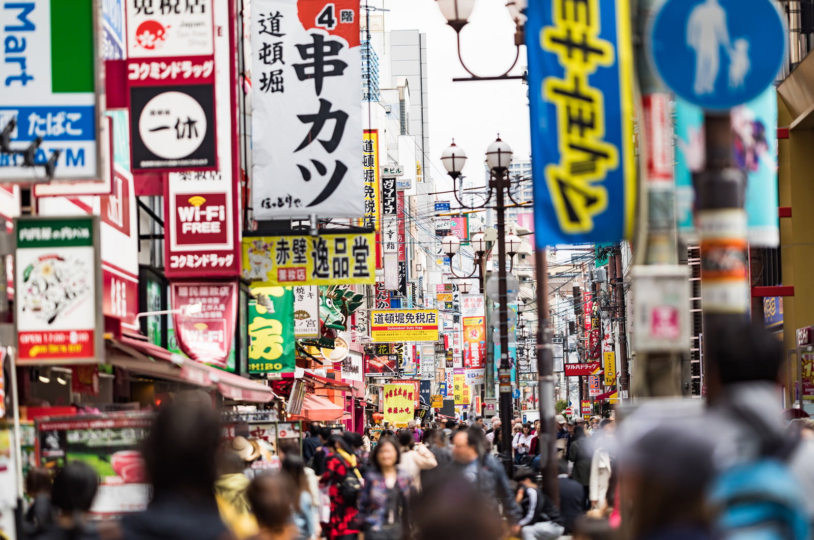 大阪道頓堀の繁華街。カラフルな看板とネオンが立ち並ぶ中、多くの人々が歩行している