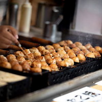 出店の手作りたこ焼き、鉄板で焼く調理風景の写真