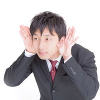「なになに？もう一回言って」っと両耳に手を当てるビジネスマンの写真
