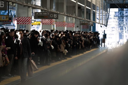 駅ホームに列をなす通勤ラッシュの人々