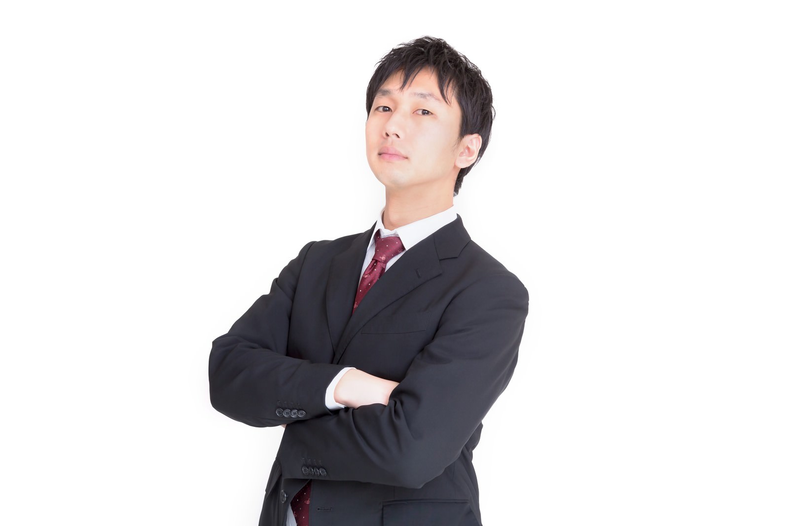 黒いスーツに赤いネクタイの男性が腕を組んで斜め上を見上げている［モデル：大川竜弥］