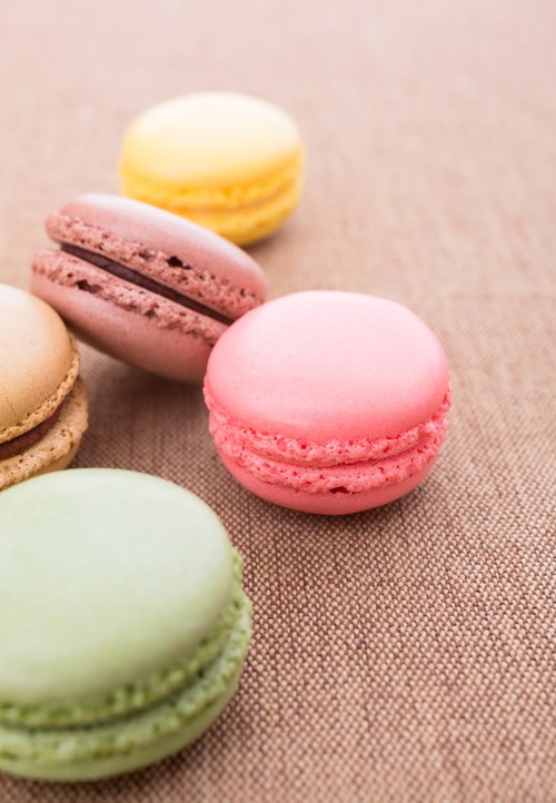 茶色い布の上に並んだカラフルなマカロン