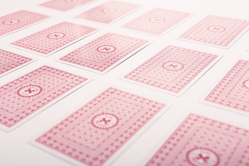 白い台の上に裏向きに並べたピンクのトランプ