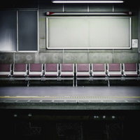 紫色の座席が並ぶ無人の駅ホームの写真