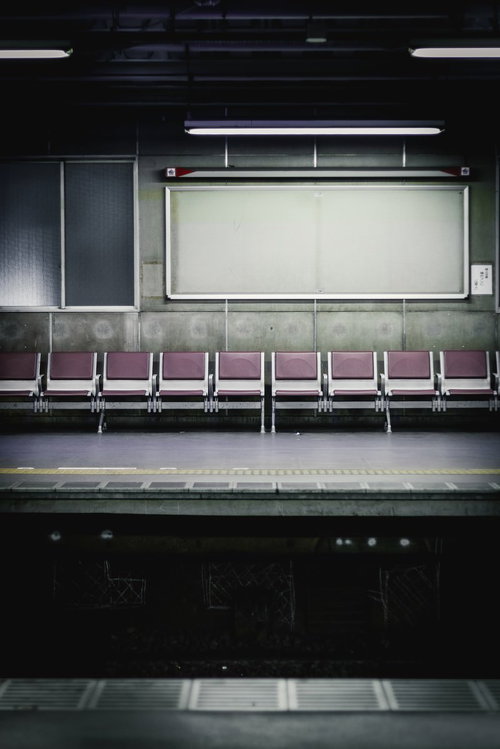 紫色の座席が並ぶ無人の駅ホーム