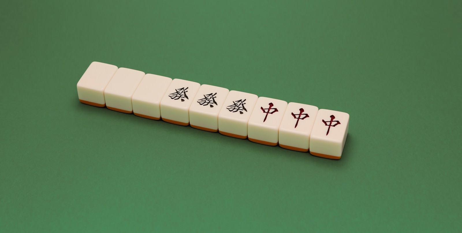 緑のマット上に並ぶ大三元の麻雀牌