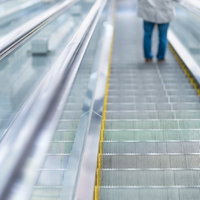 手すりと照明が続く商業施設の下りエスカレーターの奥行きの写真