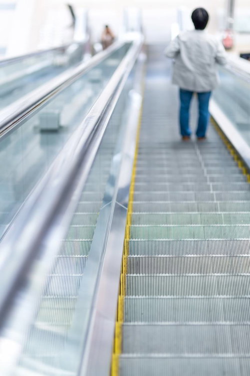 手すりと照明が続く商業施設の下りエスカレーターの奥行き