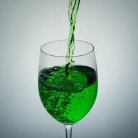 ワイングラスに注がれる緑の液体の写真