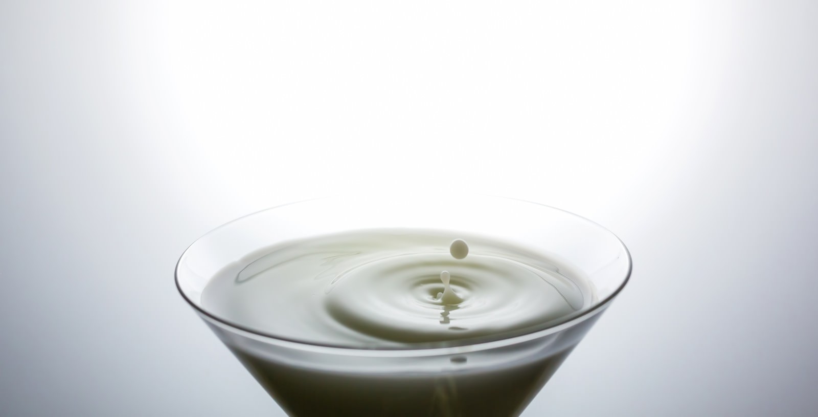 グラスの液体に水滴が落ちて波紋が広がる瞬間