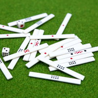 緑のフェルトに散らばる麻雀牌とサイコロの写真