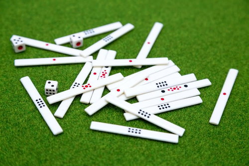 緑のフェルトに散らばる麻雀牌とサイコロ