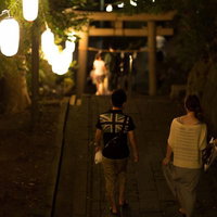 夏祭りの夜、神社参道を歩くカップルの写真