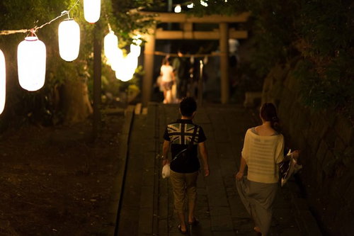 夏祭りの夜、神社参道を歩くカップル