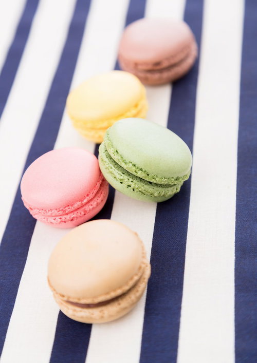 青と白の縞模様の布の上に並ぶマカロン