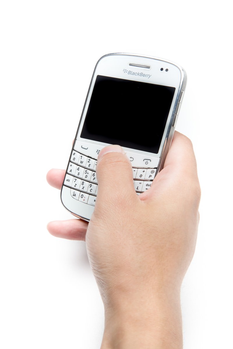 白いBlackBerryを片手で持ち親指でキーボードを操作する手