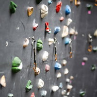 カラビナが下がるボルダリング壁とホールドの写真