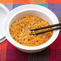カラフルな織物の上でオレンジ色の麺に箸を置いたチキンラーメンの写真