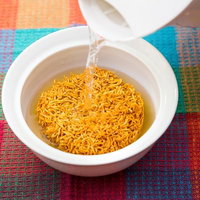 格子模様の布の上で白い容器の麺に熱湯を注ぐ瞬間の写真