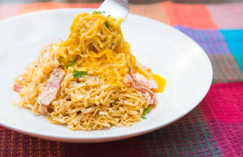 フォークで麺を持ち上げるベーコンと粉チーズの汁なしラーメン