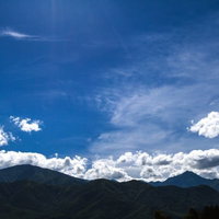 青空の下に緑の山々が連なる爽やかな山岳風景の写真