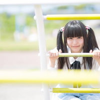 遊具の枠から顔を出すツインテールの女の子の写真