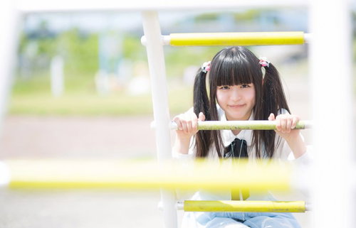 遊具の枠から顔を出すツインテールの女の子