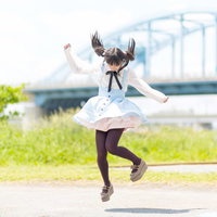 川沿いでジャンプするツインテールの女の子の写真