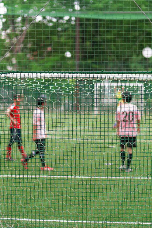 防球ネット越しに見えるサッカー選手