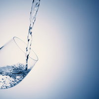 傾いたワイングラスに水をドボドボ注ぐ瞬間の写真